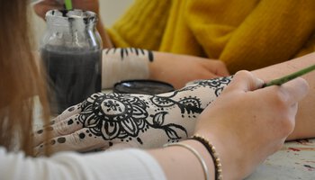 Frau malt anderer Person ein Muster auf den Arm. | © Fachschule für Heilerziehungspflege Althohenau
