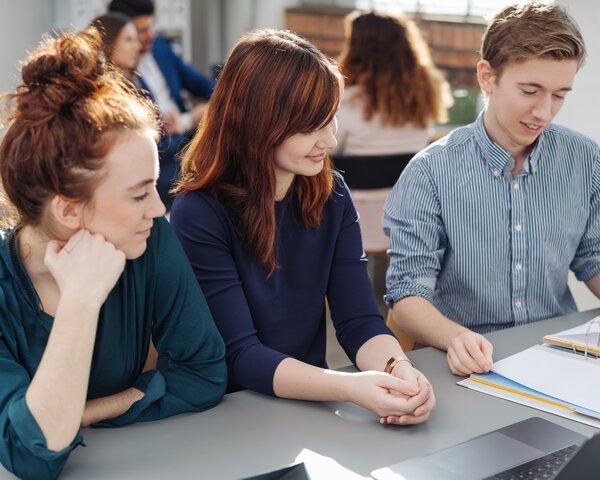 Drei glückliche Schüler lernen gemeinsam und schauen auf Lernunterlagen. | © contrastwerkstatt