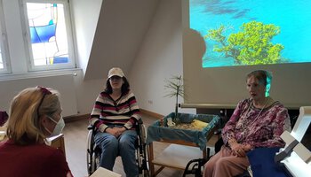 Zwei Frauen im Rollstuhl im Gespräch mit einer Caritas Mitarbeiterin | © Caritas München und Oberbayern