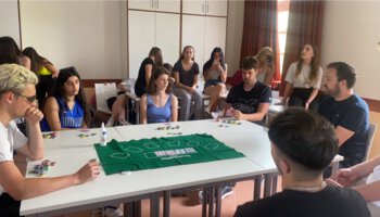 Mehrere Jugendliche sitzen an einem Tisch und spielen Poker und im Hintergrund schauen weitere Jugendliche dabei zu | © Caritas Don Bosco Berufsfachschule für Kinderpflege