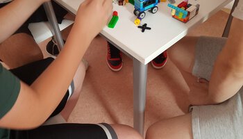 Mehrere Personen sitzen an einem Tisch der voll mit Legosteinen ist | © Caritas Don Bosco Berufsfachschule für Kinderpflege